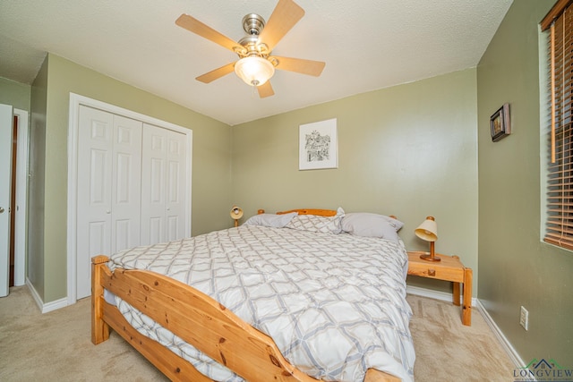 bedroom featuring ceiling fan, a closet, light carpet, and a textured ceiling