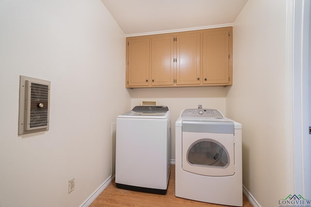 laundry room featuring cabinets, light wood-type flooring, and washer and clothes dryer