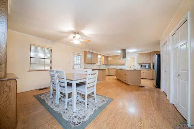 dining room with crown molding, sink, ceiling fan, and light wood-type flooring