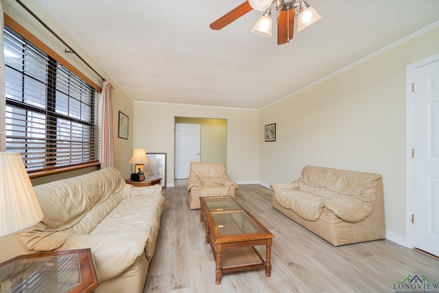 living room with ceiling fan, ornamental molding, light hardwood / wood-style floors, and a textured ceiling