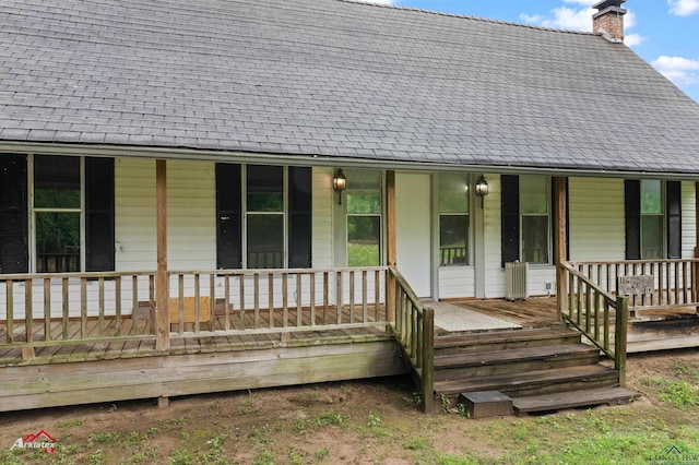 154 County Rd 117, Carthage, TX 75633 - doorway to property with covered porch, a chimney, and roof with shingles