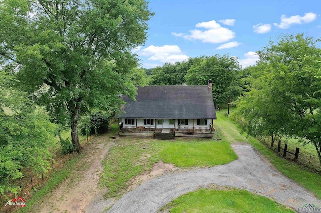154 County Rd 117, Carthage, TX 75633 - view of front of home with driveway, a porch, a chimney, and a view of trees
