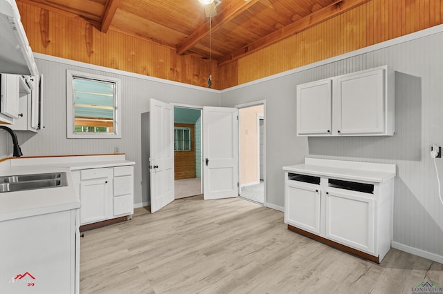 154 County Rd 117, Carthage, TX 75633 - kitchen with a wood ceiling with exposed beams, white cabinets, light countertops, light wood-type flooring, and wooden walls