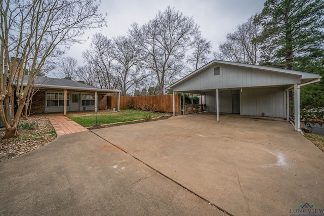 exterior space featuring brick siding, fence, driveway, a carport, and a front lawn