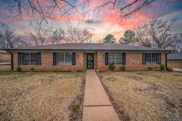 ranch-style home with a lawn and brick siding