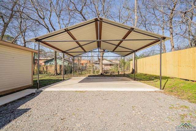 view of car parking featuring gravel driveway, a carport, and fence