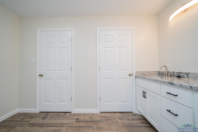 bathroom featuring vanity, baseboards, and wood finish floors