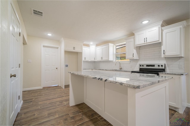 kitchen featuring visible vents, a kitchen island, stainless steel electric range oven, white cabinets, and dark wood-style flooring