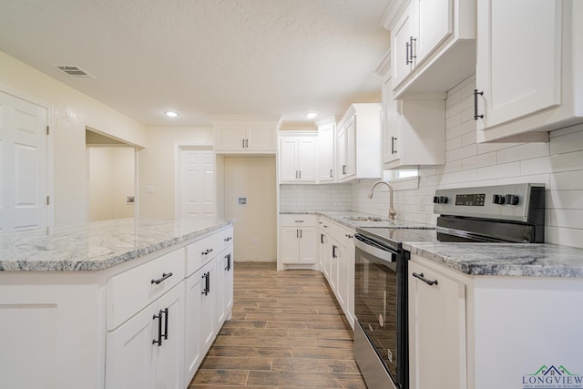 kitchen featuring a sink, tasteful backsplash, wood finished floors, white cabinetry, and stainless steel electric range