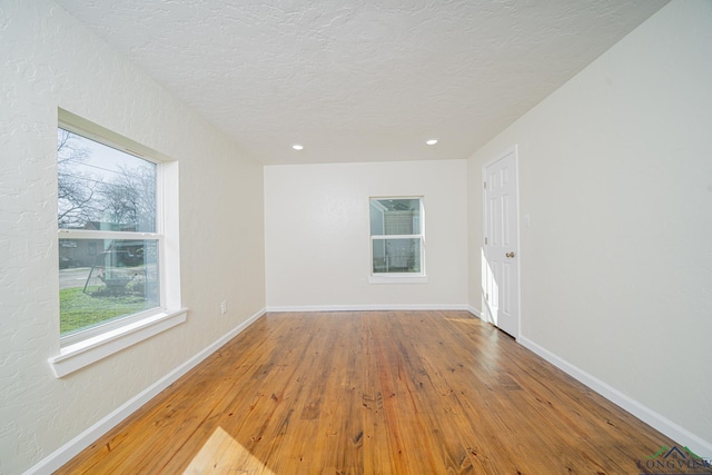 unfurnished room with hardwood / wood-style floors, recessed lighting, baseboards, and a textured ceiling