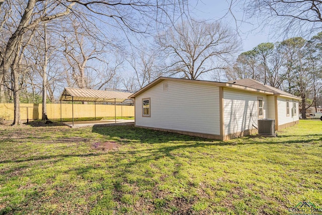 view of property exterior with fence, a lawn, and central AC