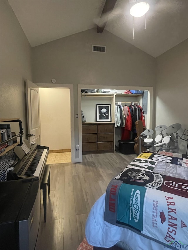 bedroom featuring vaulted ceiling with beams, light hardwood / wood-style flooring, and a closet