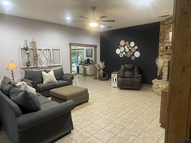 living room featuring a stone fireplace, ceiling fan, and light tile patterned flooring