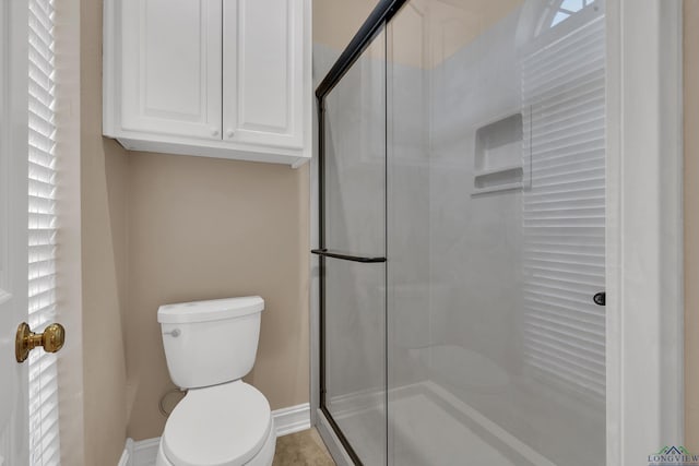 bathroom featuring tile patterned floors, toilet, and a shower with shower door