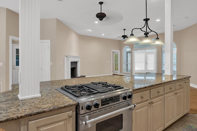 kitchen with stainless steel gas range, ceiling fan, light stone countertops, light brown cabinetry, and decorative light fixtures