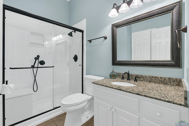 bathroom with tile patterned floors, vanity, toilet, and a shower with shower door