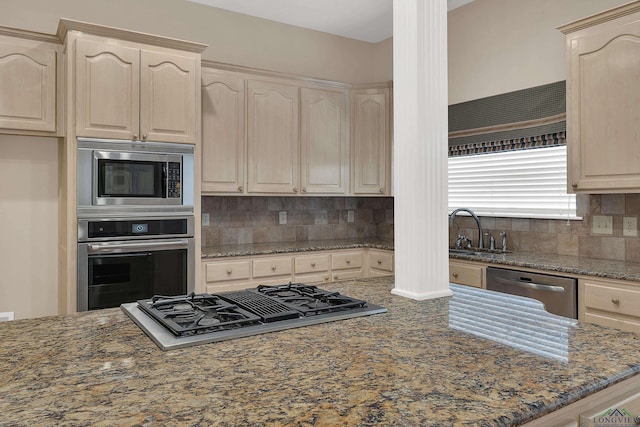 kitchen featuring tasteful backsplash, sink, appliances with stainless steel finishes, and dark stone counters