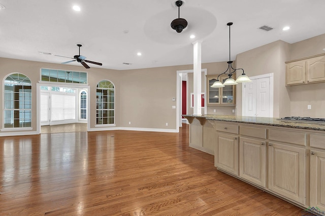 kitchen with stainless steel gas stovetop, light brown cabinets, light hardwood / wood-style flooring, ceiling fan, and light stone counters