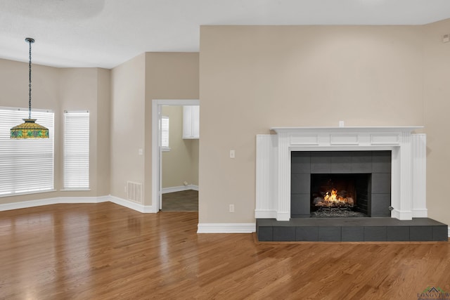 unfurnished living room with a tile fireplace and wood-type flooring