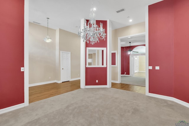 empty room with carpet floors and ceiling fan with notable chandelier