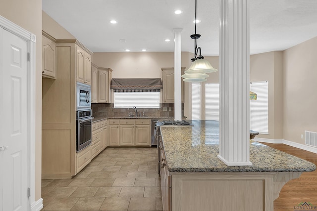 kitchen with light brown cabinetry, stainless steel appliances, dark stone counters, and sink