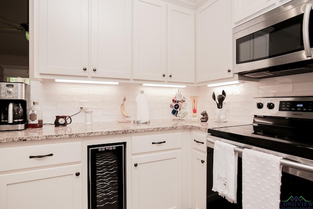 2131 Page Creek Trl, Longview, TX 75601 - kitchen featuring stainless steel appliances, wine cooler, white cabinetry, tasteful backsplash, and light stone counters