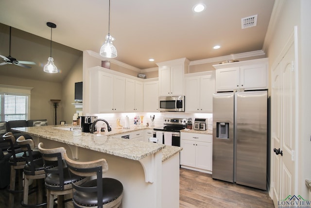 2131 Page Creek Trl, Longview, TX 75601 - kitchen with stainless steel appliances, a peninsula, white cabinets, light stone counters, and pendant lighting