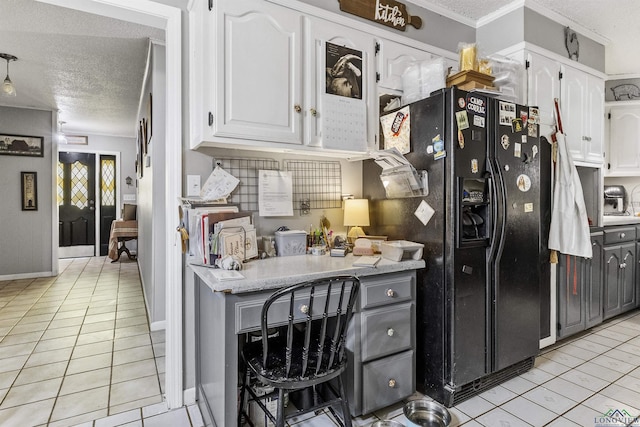 kitchen featuring light tile patterned flooring, black fridge, white cabinetry, and a textured ceiling
