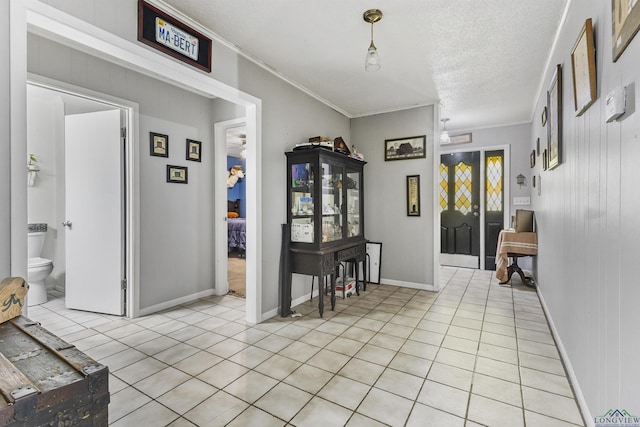 tiled entryway featuring crown molding and a textured ceiling