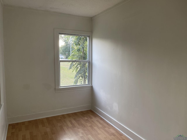 spare room featuring crown molding, plenty of natural light, light hardwood / wood-style floors, and a textured ceiling