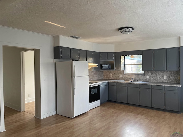 kitchen with tasteful backsplash, gray cabinets, light hardwood / wood-style floors, and white appliances