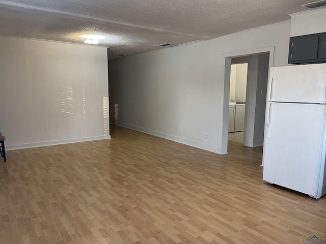 unfurnished living room featuring washing machine and clothes dryer, light hardwood / wood-style flooring, and a textured ceiling