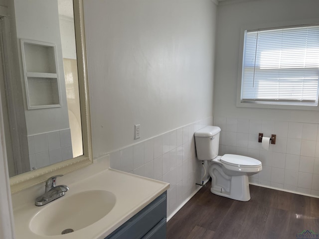 bathroom featuring wood-type flooring, vanity, toilet, and tile walls