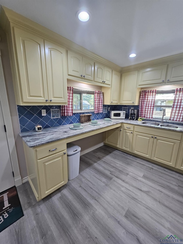 kitchen with cream cabinets, a healthy amount of sunlight, sink, and light hardwood / wood-style flooring