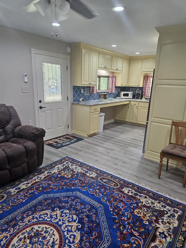 kitchen featuring tasteful backsplash, ceiling fan, cream cabinets, and light wood-type flooring