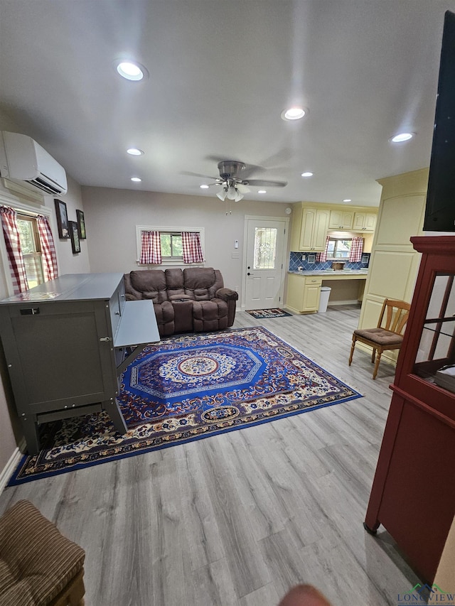 living room featuring ceiling fan, light hardwood / wood-style flooring, and a wall mounted AC