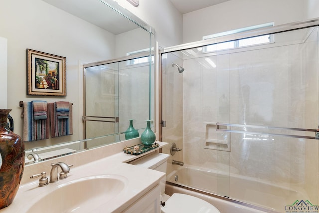 full bathroom featuring vanity, combined bath / shower with glass door, and toilet