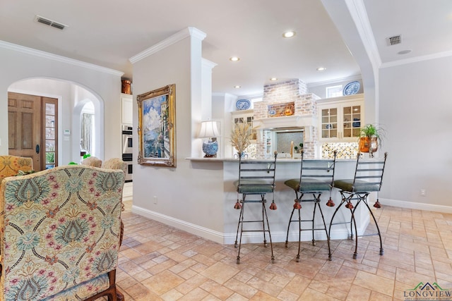 kitchen with crown molding, a breakfast bar, kitchen peninsula, and backsplash