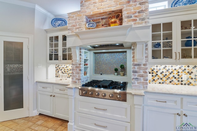 kitchen with white cabinetry, stainless steel gas stovetop, crown molding, and decorative backsplash