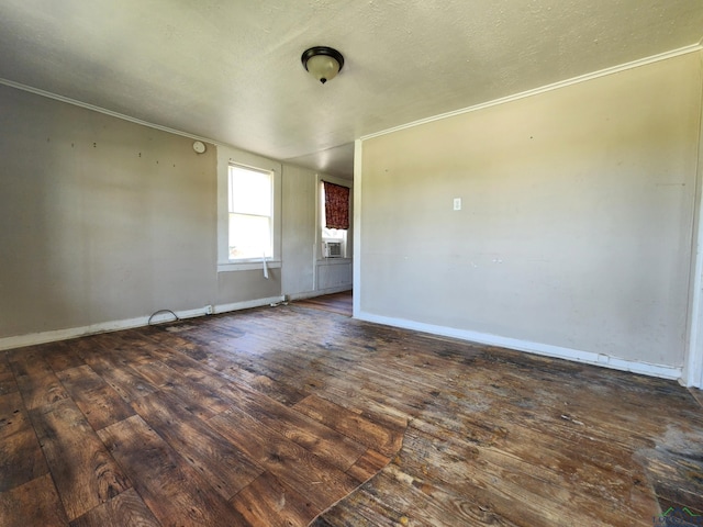 spare room with crown molding, dark wood-type flooring, and a textured ceiling