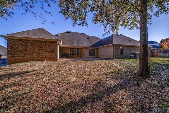 rear view of property featuring central AC unit, a patio area, brick siding, fence, and a yard