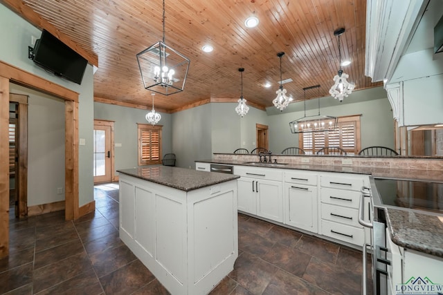 kitchen with an inviting chandelier, a sink, white cabinets, and decorative light fixtures