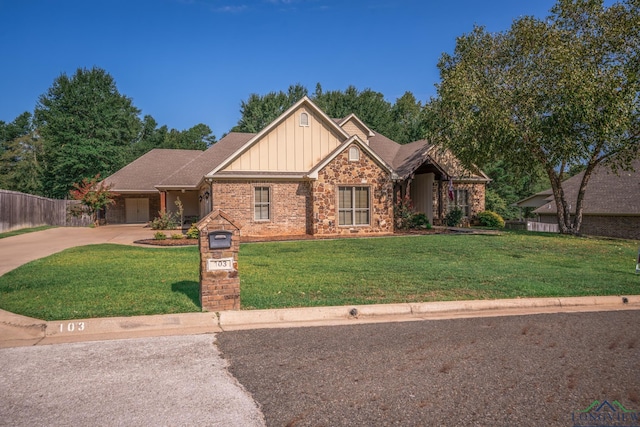 view of front of property featuring board and batten siding, brick siding, fence, a front lawn, and concrete driveway