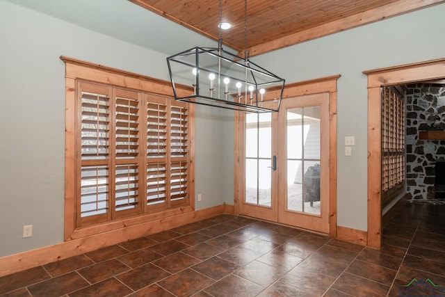unfurnished dining area featuring french doors, baseboards, a notable chandelier, and wooden ceiling