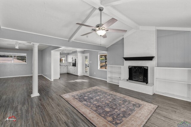 unfurnished living room with vaulted ceiling with beams, dark hardwood / wood-style flooring, a brick fireplace, and ceiling fan