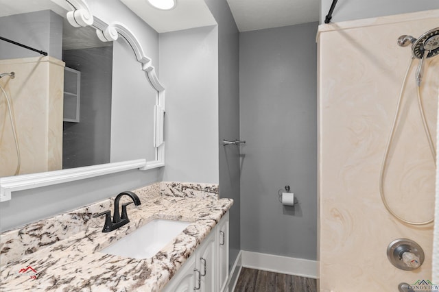 bathroom with walk in shower, vanity, and hardwood / wood-style flooring