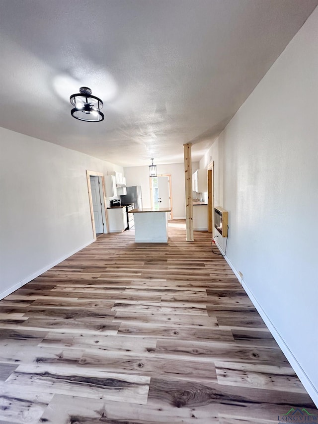 unfurnished living room with light hardwood / wood-style floors, heating unit, and a textured ceiling