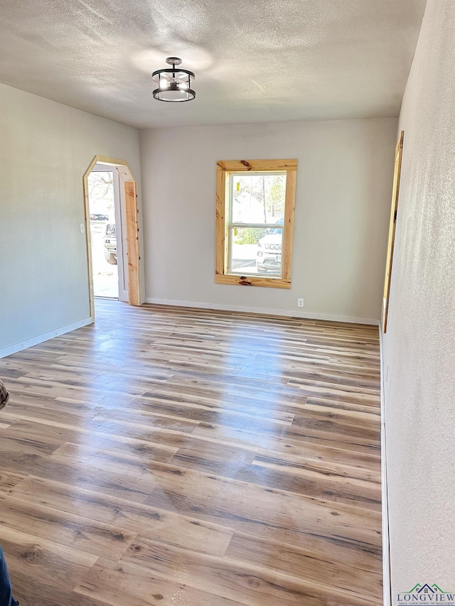 unfurnished room with hardwood / wood-style flooring and a textured ceiling