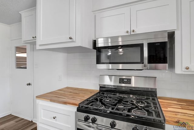 kitchen featuring wooden counters, stainless steel appliances, white cabinetry, and tasteful backsplash