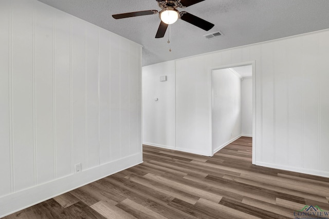 empty room featuring ceiling fan, wood-type flooring, and a textured ceiling